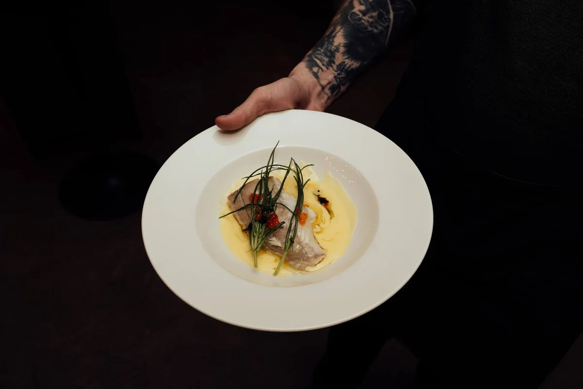 A chef plating a fish dish with caviar in the kitchen at The Hackney