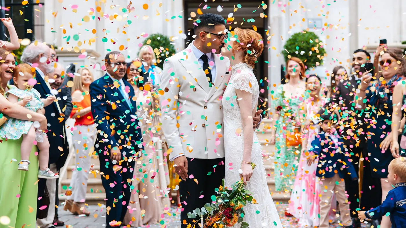 Couple kissing in a shower of confetti on the steps outside a London register office after their ceremony