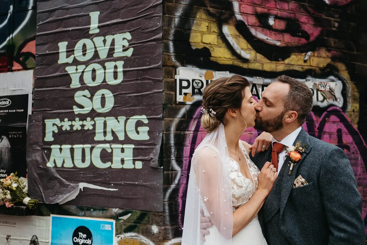 Sarah and Lee sharing a kiss against East London street art, captured by Ollie Hinds Photography